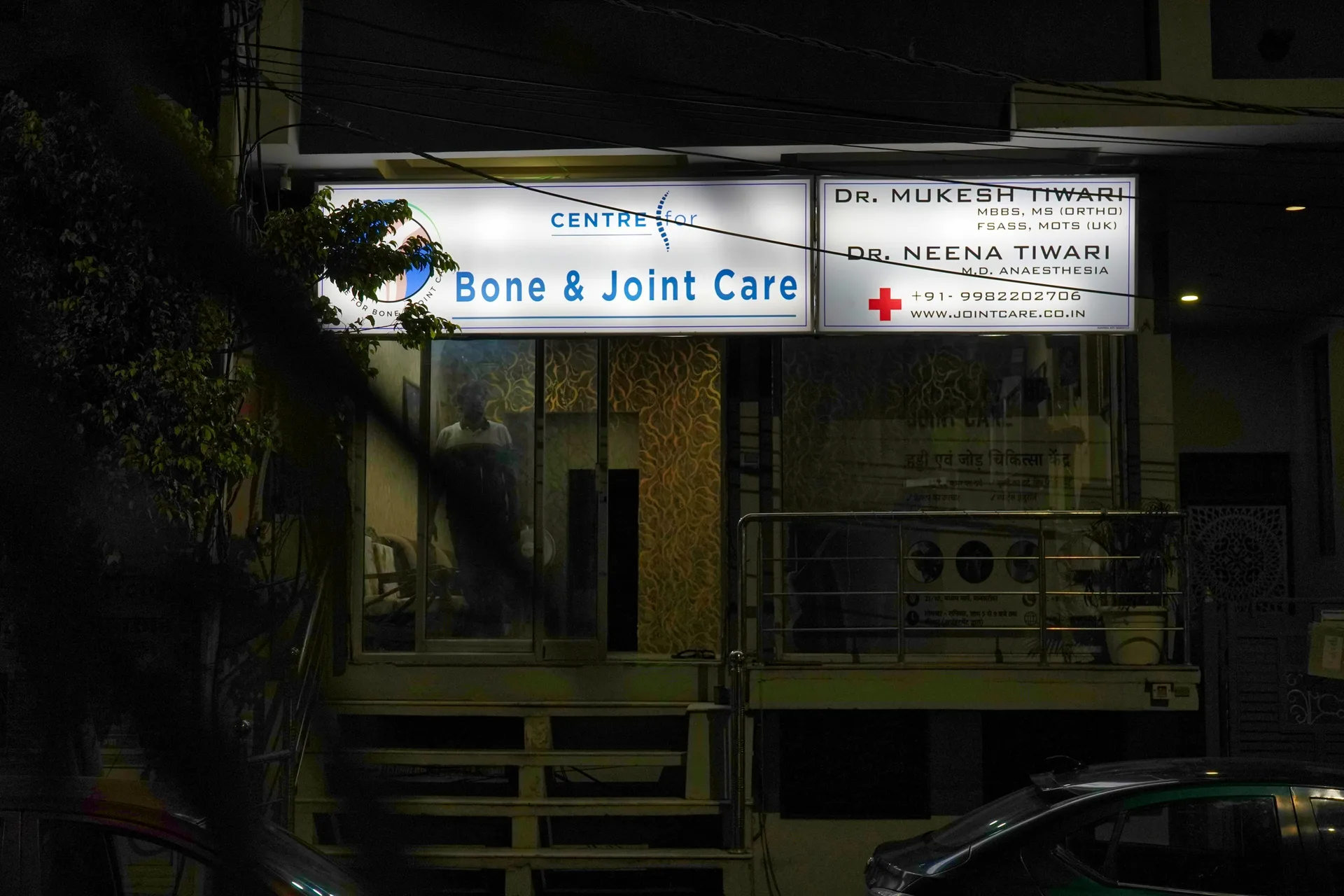 Wide night view of the clinic frontage with its illuminated signboards, entrance stairs and street parking
